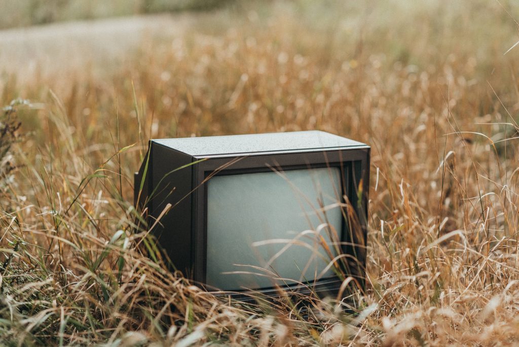 A CRT TV in a field looking for someone who takes old TVs